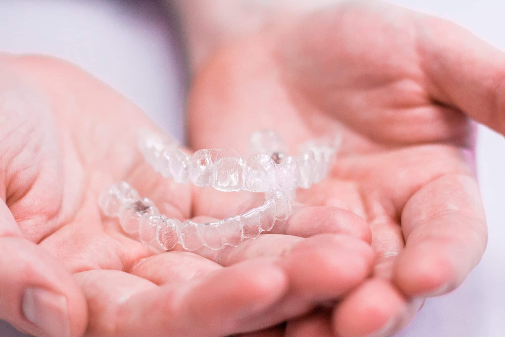 Hands holding two Invisalign trays